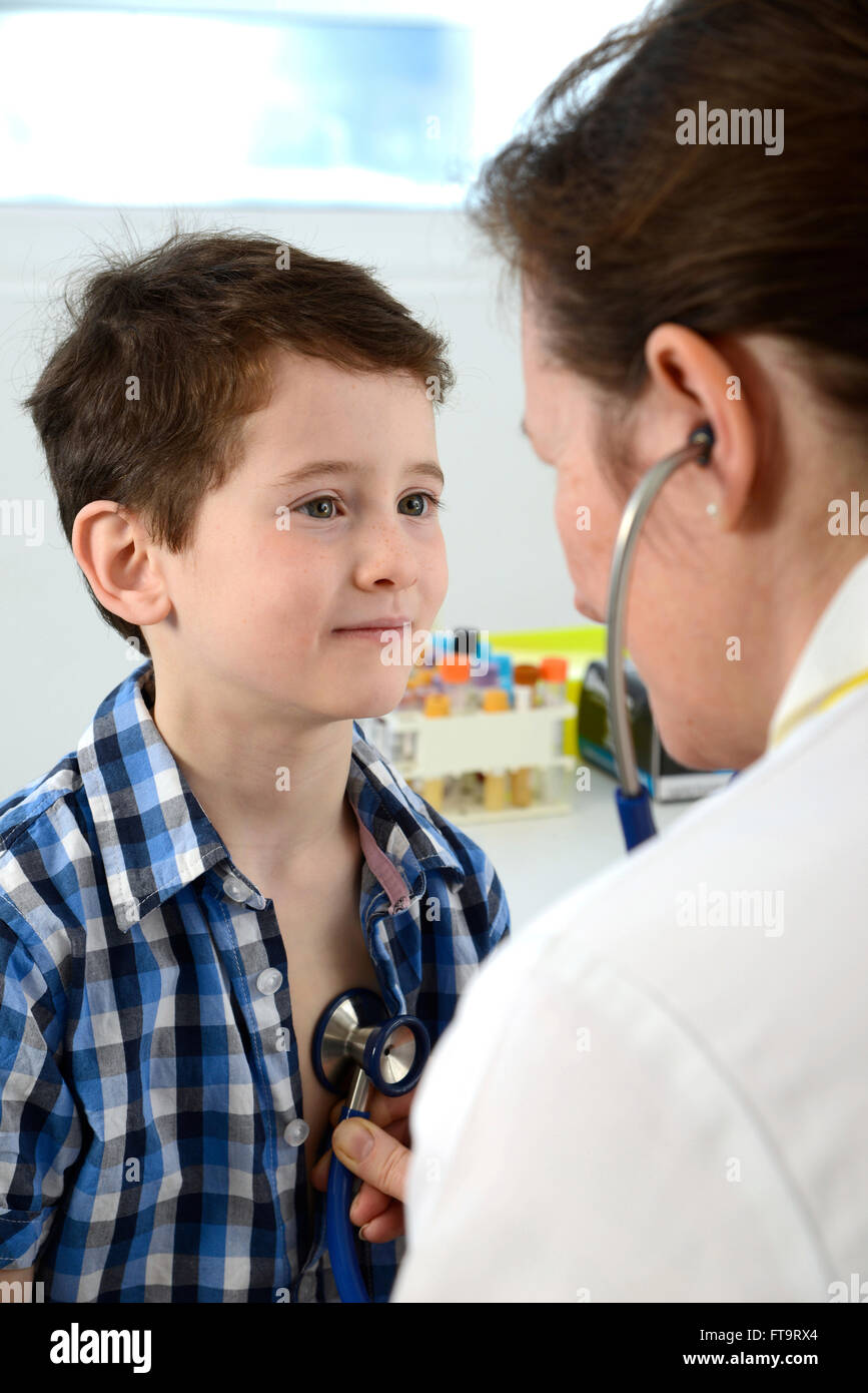 Parution du modèle. Pratique générale médecin appuie sur un stéthoscope sur la poitrine d'un jeune garçon. Banque D'Images