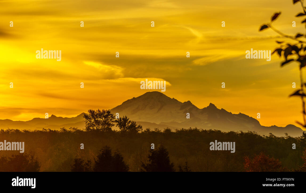 Le lever de soleil derrière le mont Baker, un volcan dormant dans l'état de Washington aux États-Unis sur un matin d'automne brumeux comme vu de la vallée du Fraser, en Colombie-Britannique, Canada Banque D'Images