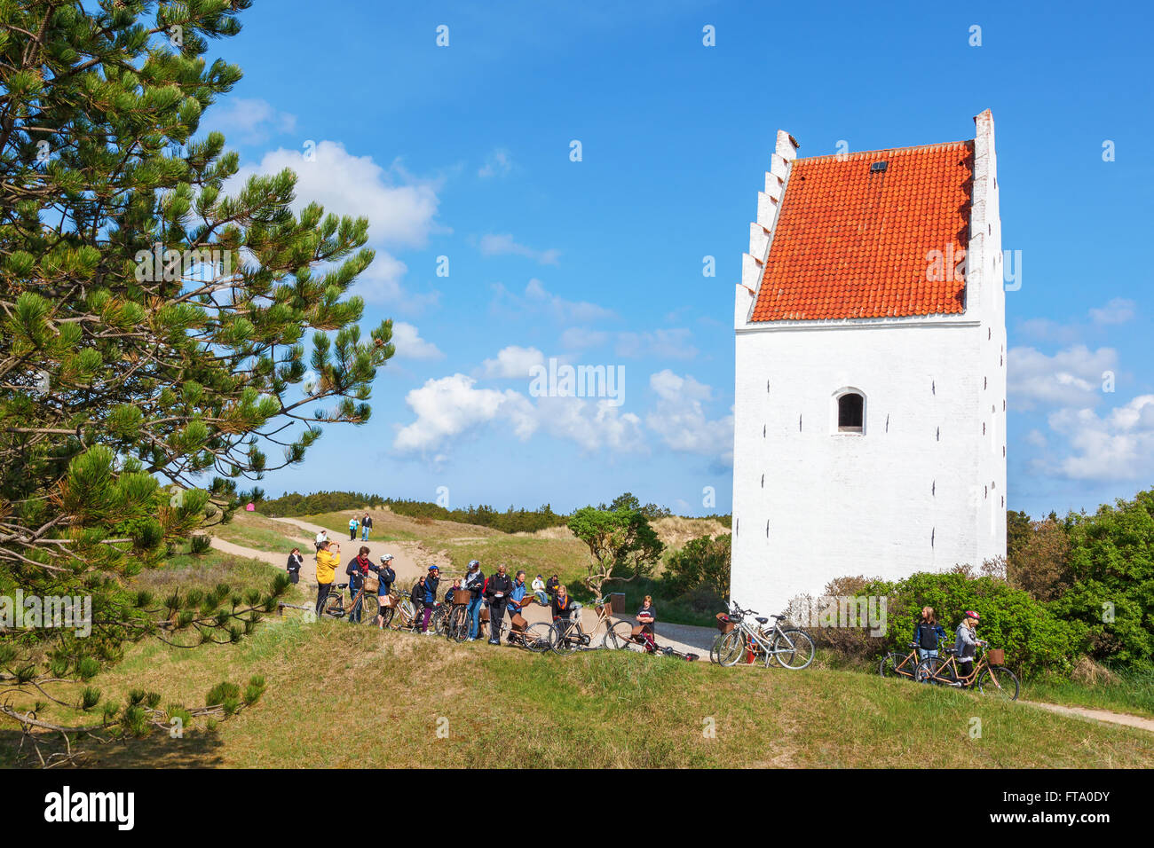 Les jeunes sur un vélo voyage à l'Église en Sand-Covered Skagen Banque D'Images