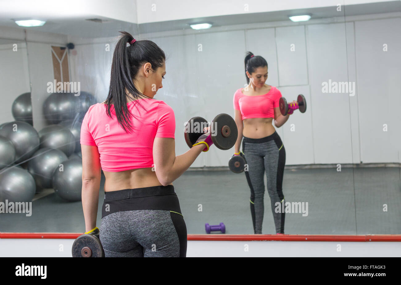 Girl doing biceps workout en face d'un miroir Banque D'Images