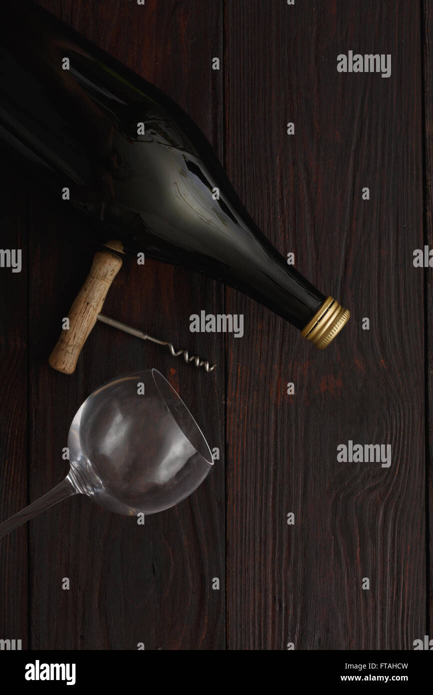 Bouteille de vin rouge à côté de verre vide avec tire-bouchon de table en bois. Mise à plat, vue ci-dessus, copie espace,style clair-obscur Banque D'Images