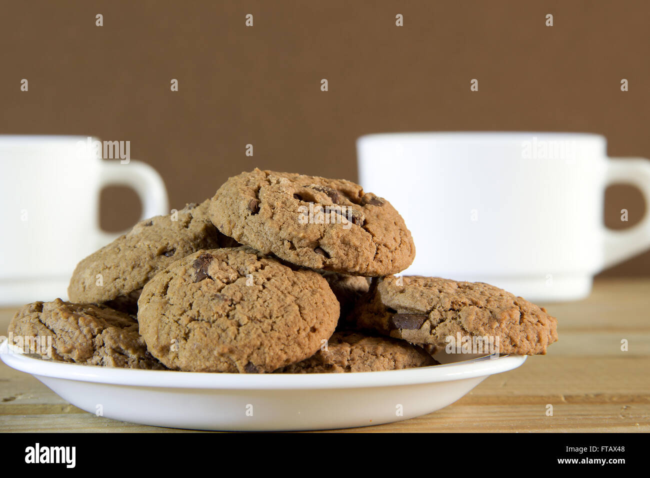 Cookies au chocolat et deux tasses de thé sur une table en bois Banque D'Images