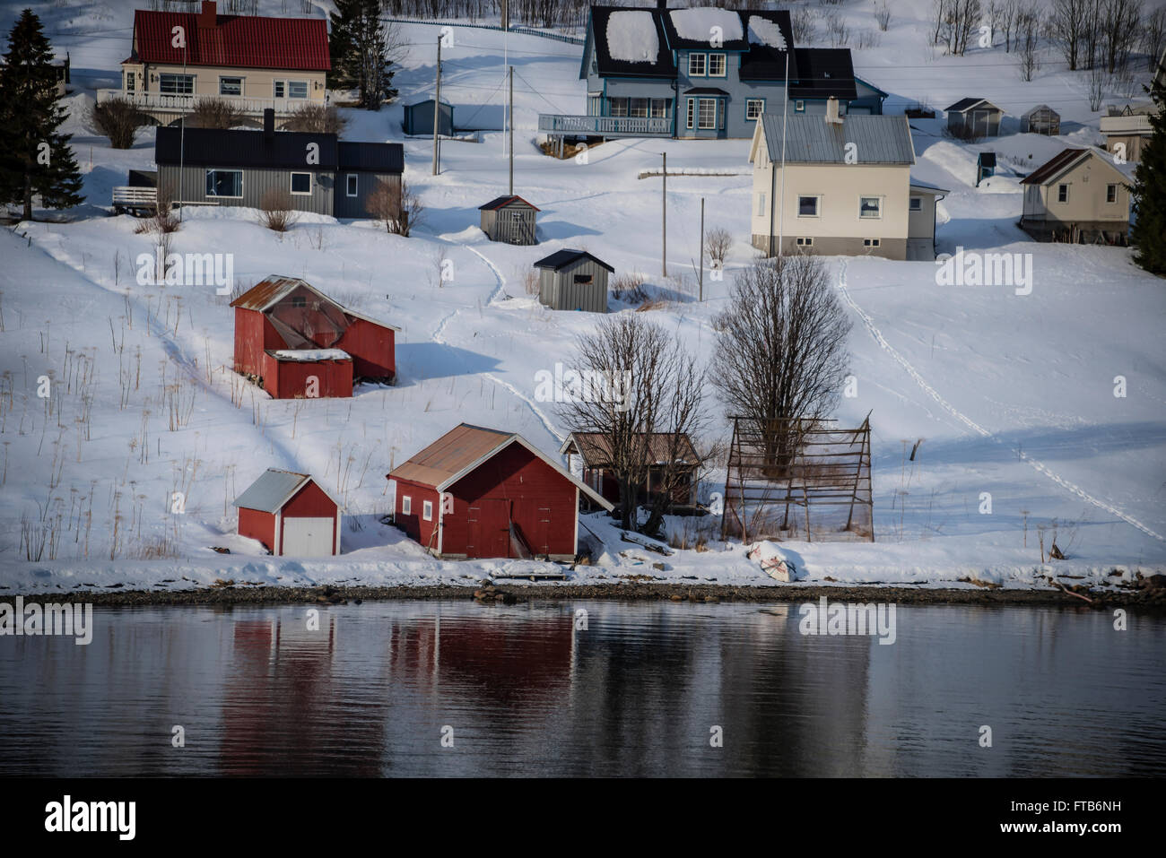 Bateau rouge maisons au bord d'un fjord près de Tromso, Norvège. Banque D'Images