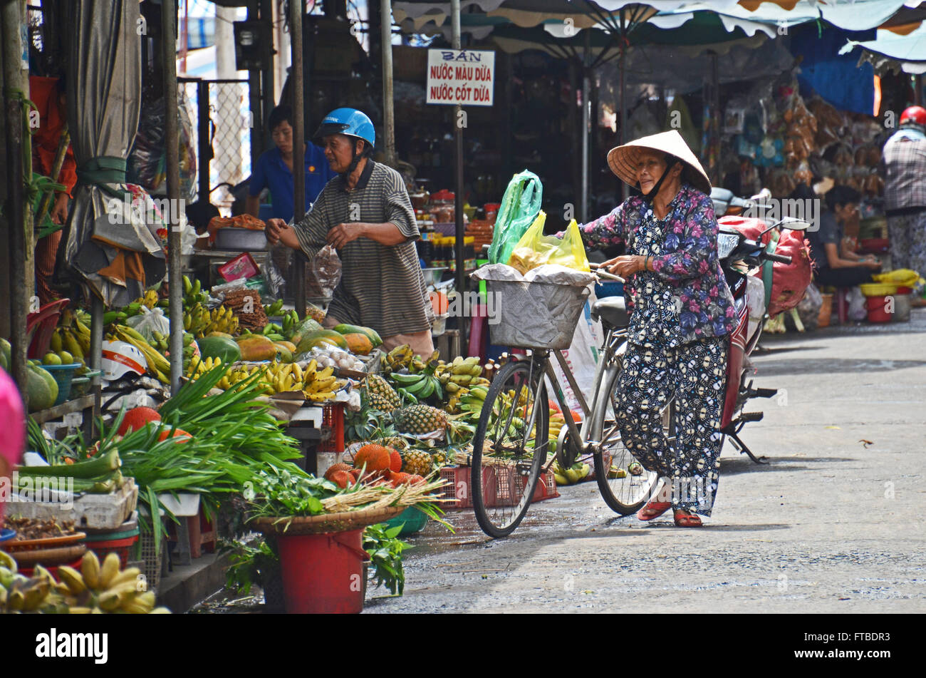 Une femme boutiques pour les fruits et légumes dans le marché à Ben Tre dans le Delta du Mekong, Vietnam Banque D'Images