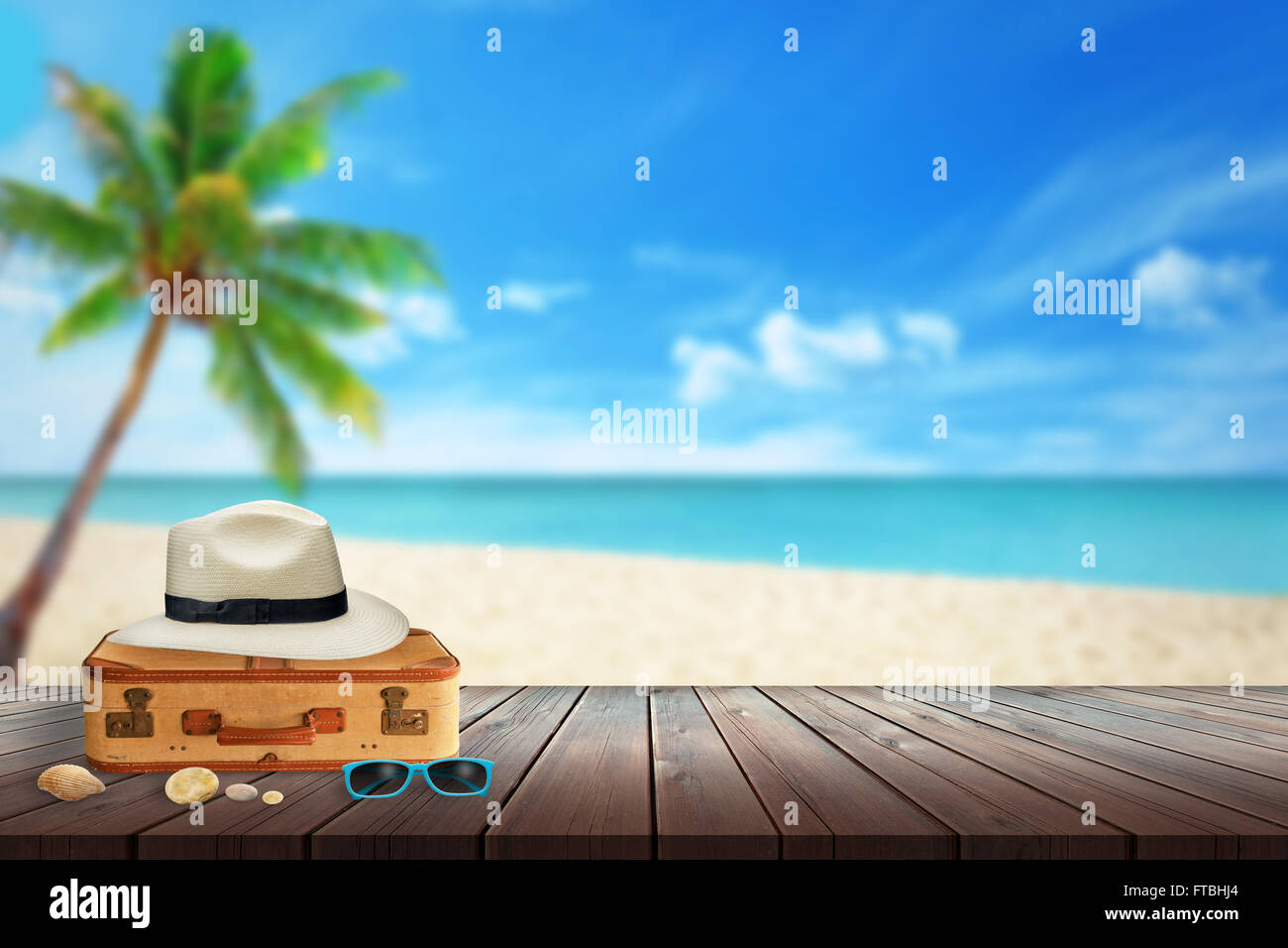 Hat, valise, lunettes de soleil, plage de shell sur table. Espace libre pour le texte. Plage, Mer, palmiers et ciel bleu en arrière-plan. Banque D'Images
