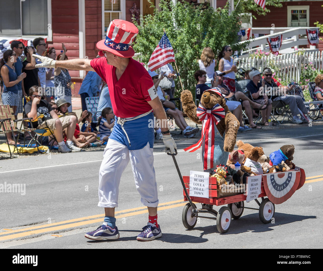 Un homme habillé en rouge, blanc et bleu tire une charrette pleine d'ours au cours d'une parade à la vallée de la Mohawk, jour de l'indépendance. Banque D'Images