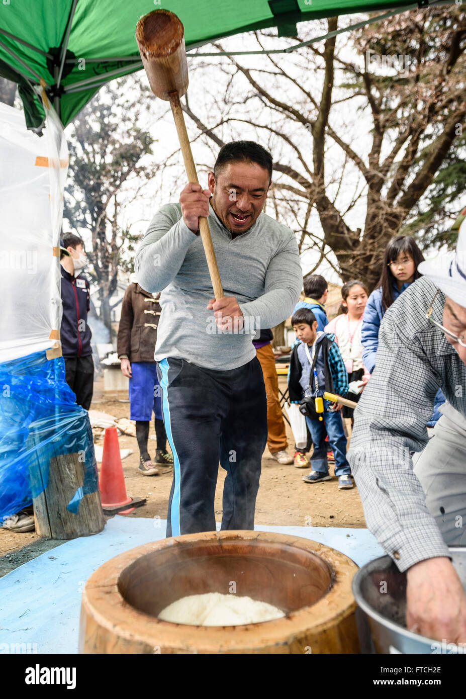 26 mars 2016 - Keizo Matsuda, un lutteur professionnel local, a été invité à l'événement pour divertir les enfants et de contribuer à faire du mochi. Ici il livres le riz vapeur dans un mortier en bois. © Ben Weller/AFLO/Alamy Live News Banque D'Images