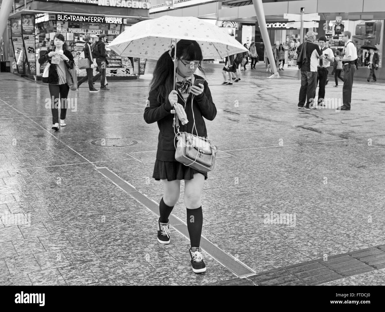 Girl texting in the rain Banque D'Images