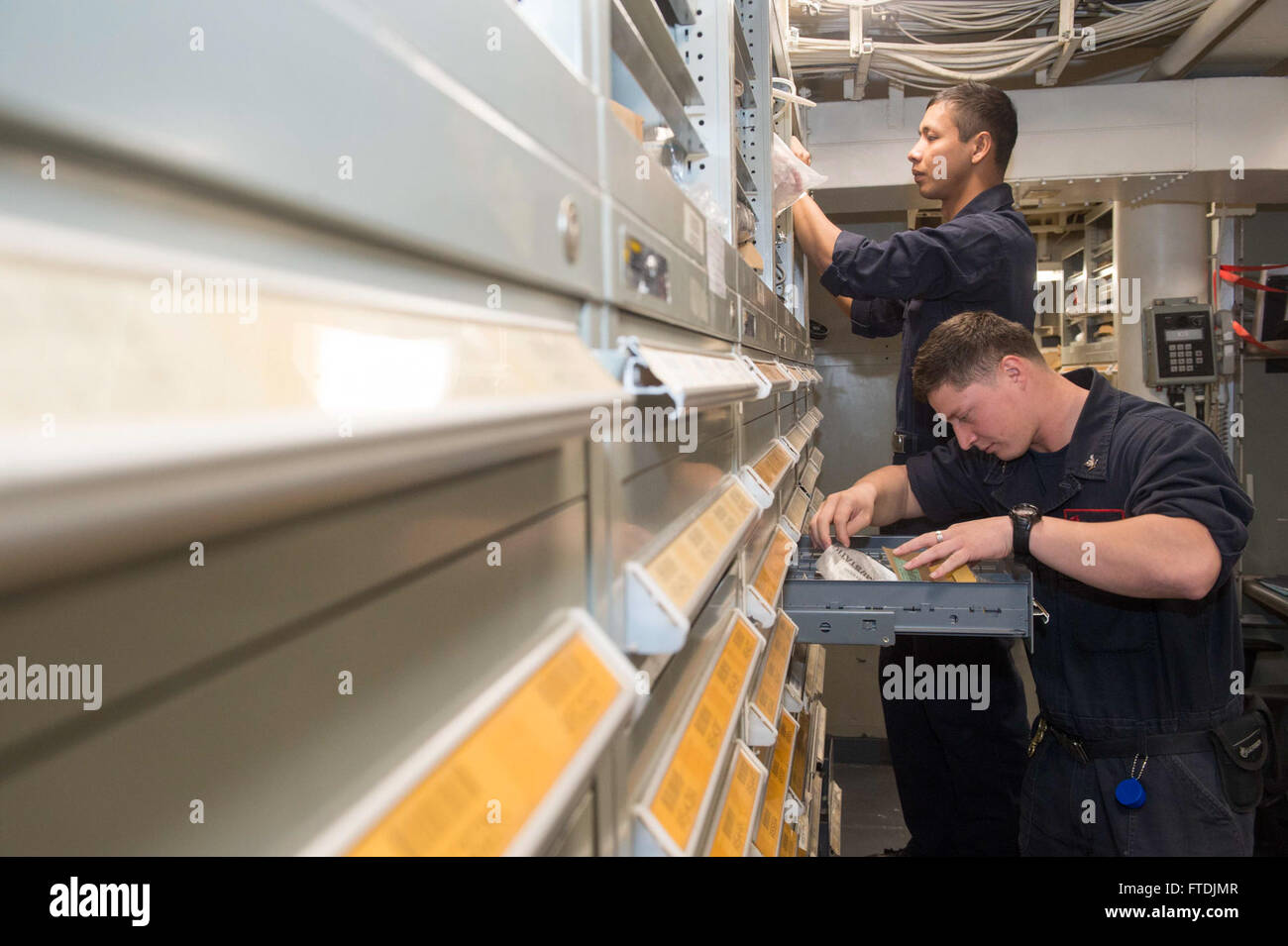 Le 10 décembre 2015, les spécialistes de la logistique de 3e classe S. Bailowas et F. Beltran à bord de l'USS Ramage (DDG 61) localisent les pièces de réparation pour soutenir les efforts de maintenance. Le destroyer à missiles guidés mène des opérations dans le cadre du Harry S. Truman Carrier Strike Group dans la zone de la 6e flotte américaine, soutenant les intérêts de sécurité nationale des États-Unis en Europe et en Afrique. Banque D'Images