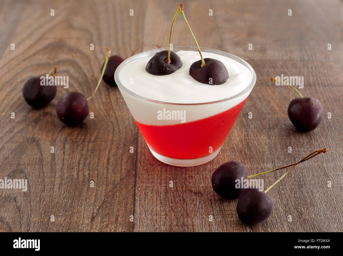 Dessert frais d'été avec des cerises noires, des yaourts et de la gelée rouge. Banque D'Images