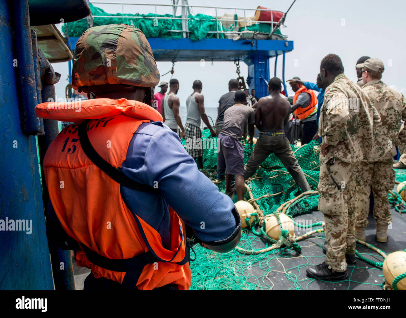 160320-N-EZ054-072 Golfe de Guinée (20 mars 2016) - Un membre de l'équipe d'embarquement de la Marine ghanéenne monte la garde comme pêcheur sont chargés de poser les filets de pêche au cours d'une pêche illégale dans le cadre de l'exercice de scénario Obangame Express 2016/saharienne, 20 mars. Saharienne/Obangame Express, un des trois exercices série express régionale africaine facilitée par les Forces navales des États-Unis États-Unis/Europe - Afrique 6e Flotte, vise à accroître la coopération régionale, la connaissance du domaine maritime, les pratiques de partage de l'information et améliorer l'interopérabilité entre les forces participantes afin d'améliorer la sécurité maritime et regio Banque D'Images