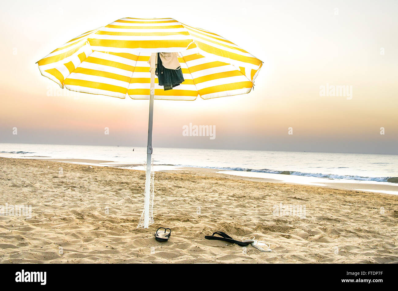 Parapluie jaune isolé sur la plage au coucher du soleil dans les Pouilles Banque D'Images