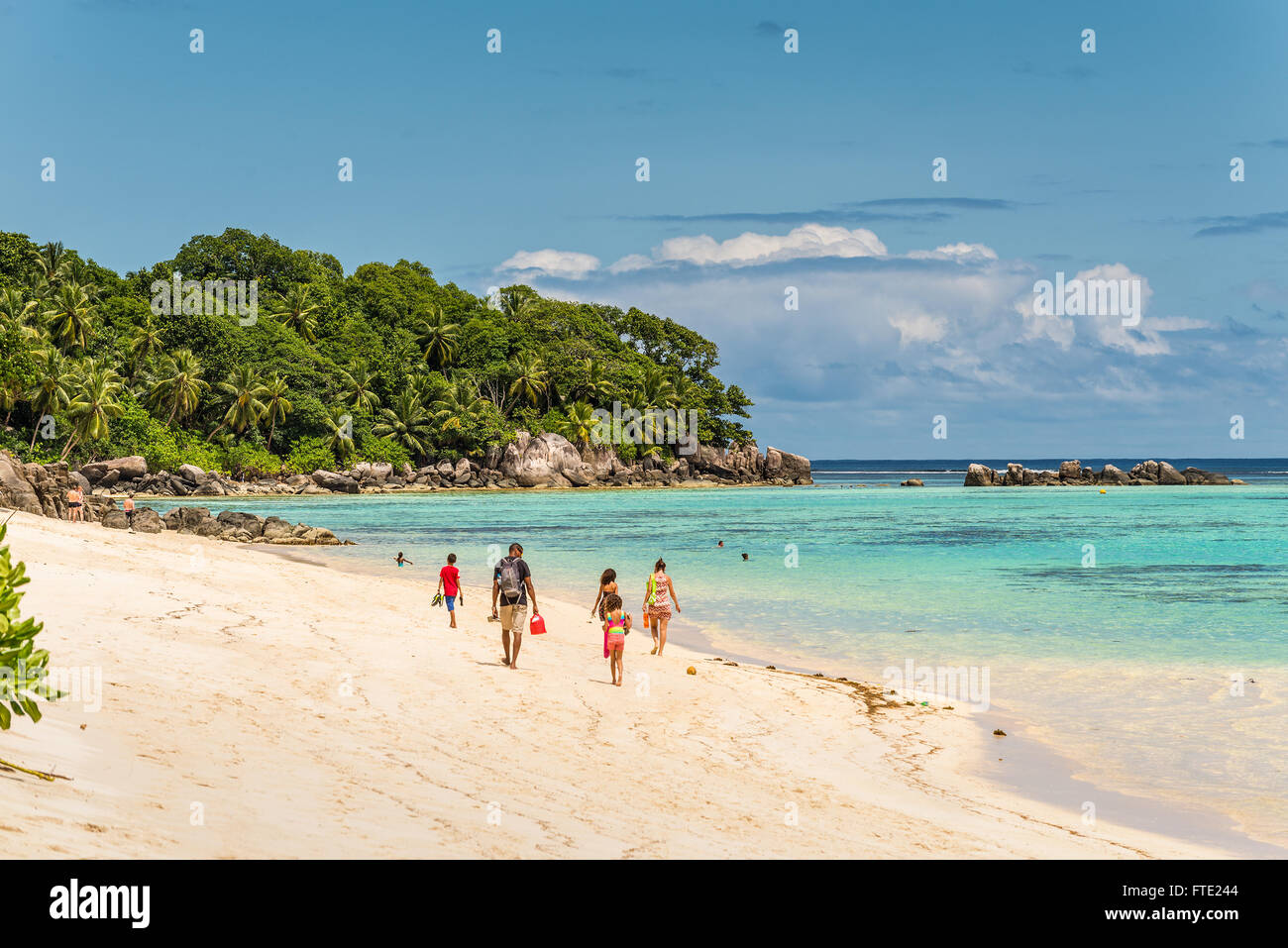 Les gens qui marchent dans le sable dans le spectaculaire plage de Anse Royale Banque D'Images