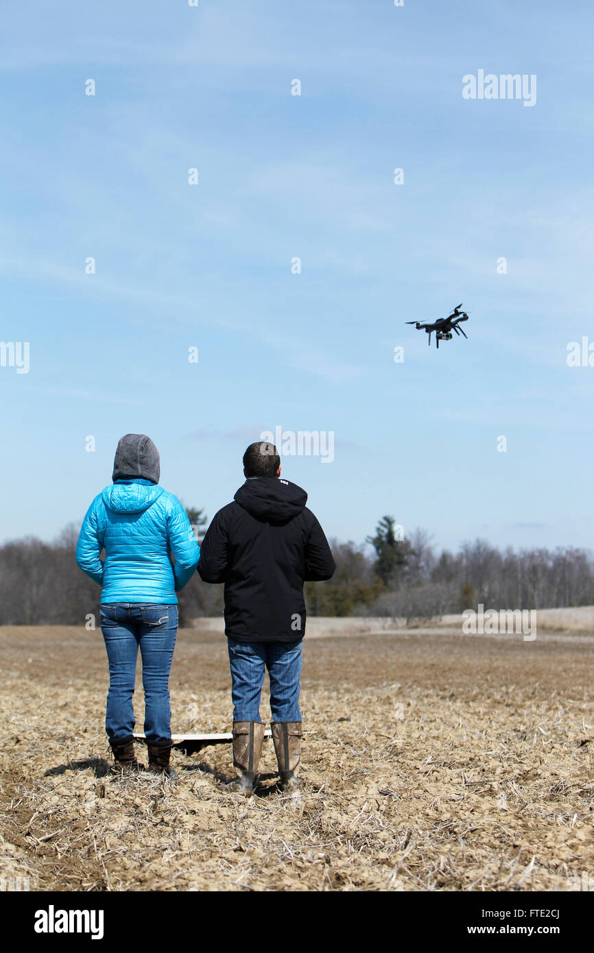 Un jeune couple aux commandes d'un drone au-dessus d'un champ. Banque D'Images