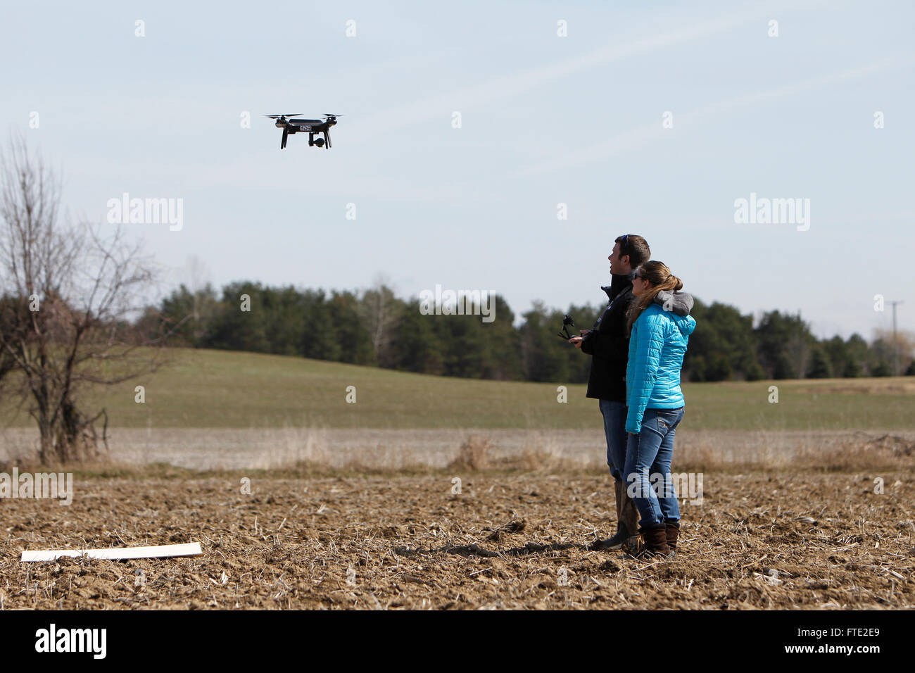 Deux personnes aux commandes d'un drone au-dessus d'un champ. Banque D'Images