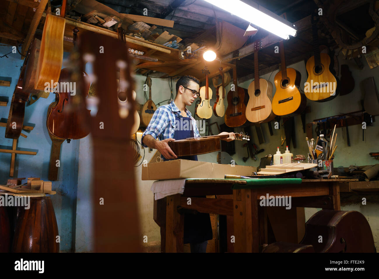 Luthier magasin et instruments de musique acoustique : un jeune adulte  artisan corrige un vieux classique de la guitare, puis le stocke dans une  boîte en carton Photo Stock - Alamy