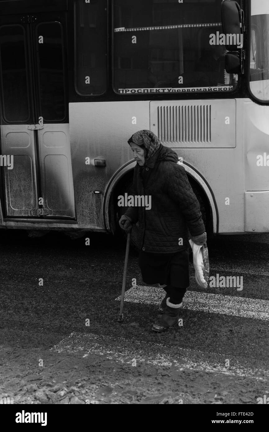 UFA - RUSSIE 1ER MARS 2016 - Une vieille femme utilise un passage pour piétons pour traverser une rue principale perspective octobre qu'un bus se déplacer Banque D'Images