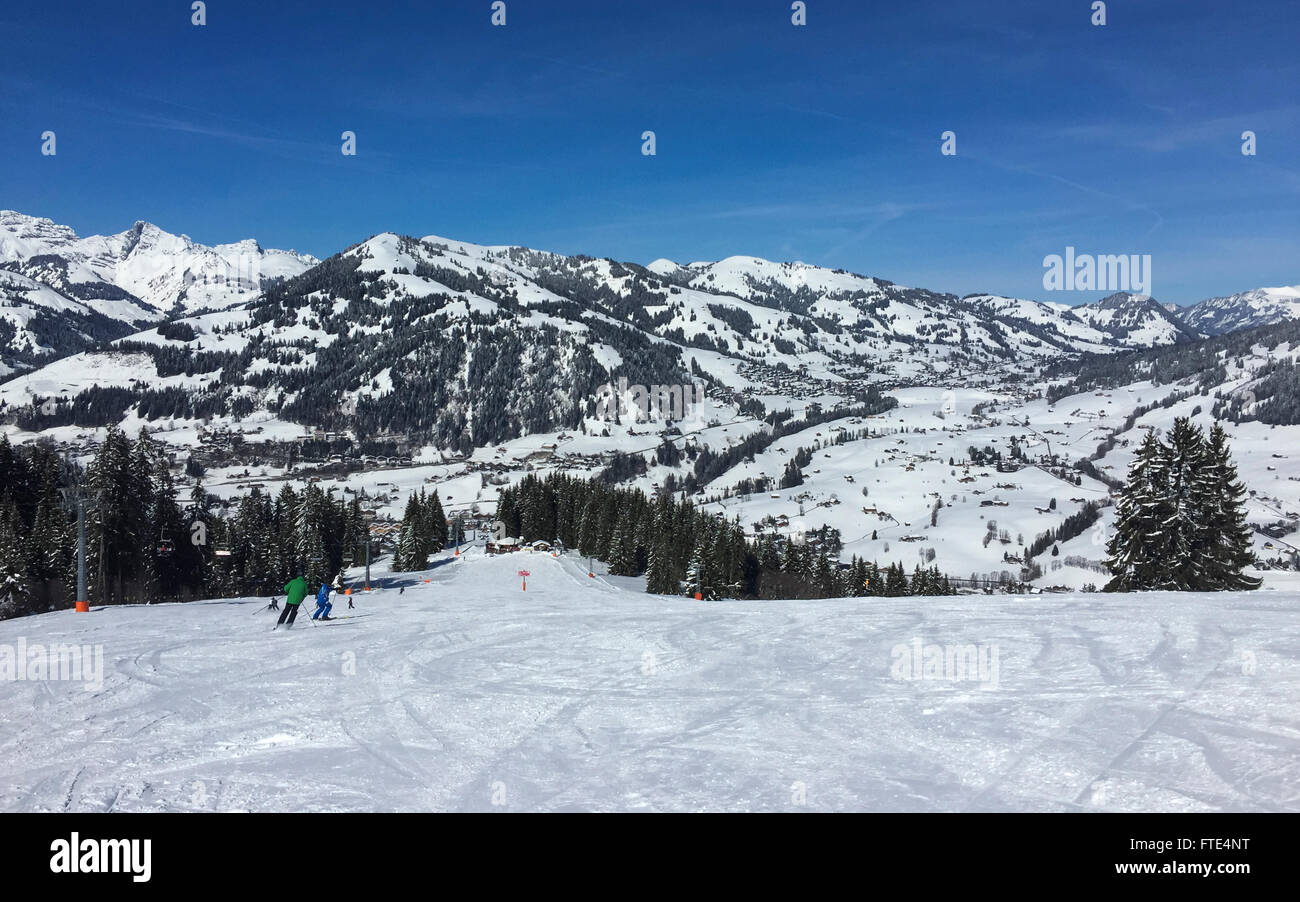 Pente de ski dans la zone de sport hiver à Gstaad. Dans l'arrière-plan les montagnes et le village de Schönried. Gstaad, Suisse. Banque D'Images