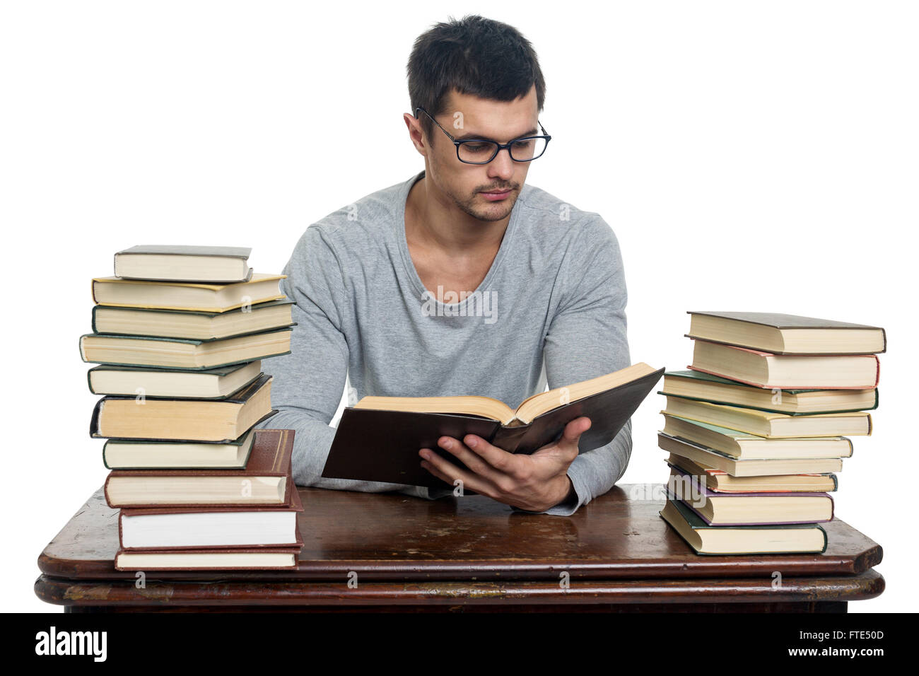 Jeune homme à lunettes lit livre à table Photo Stock - Alamy