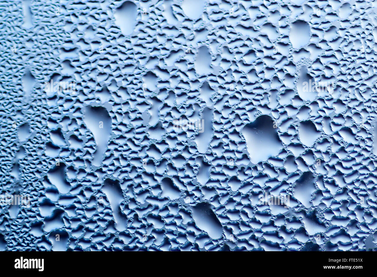 La Condensation forme des gouttelettes d'eau sur la surface d'une fenêtre en verre clair de l'intérieur de la chambre. Sombre ciel bleu couleur texture Banque D'Images