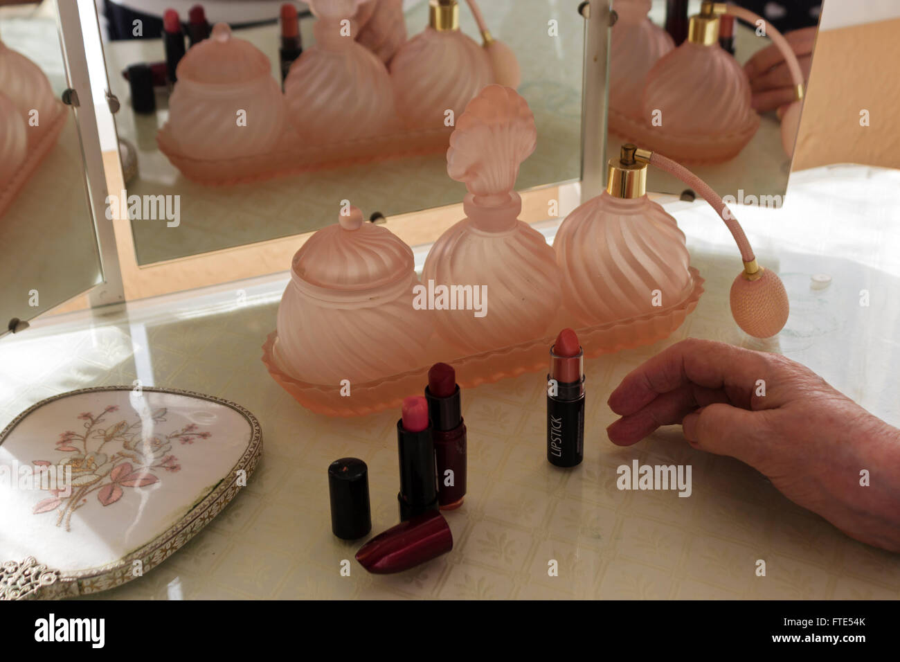 Flacons à parfum en verre rose sur une coiffeuse. Banque D'Images