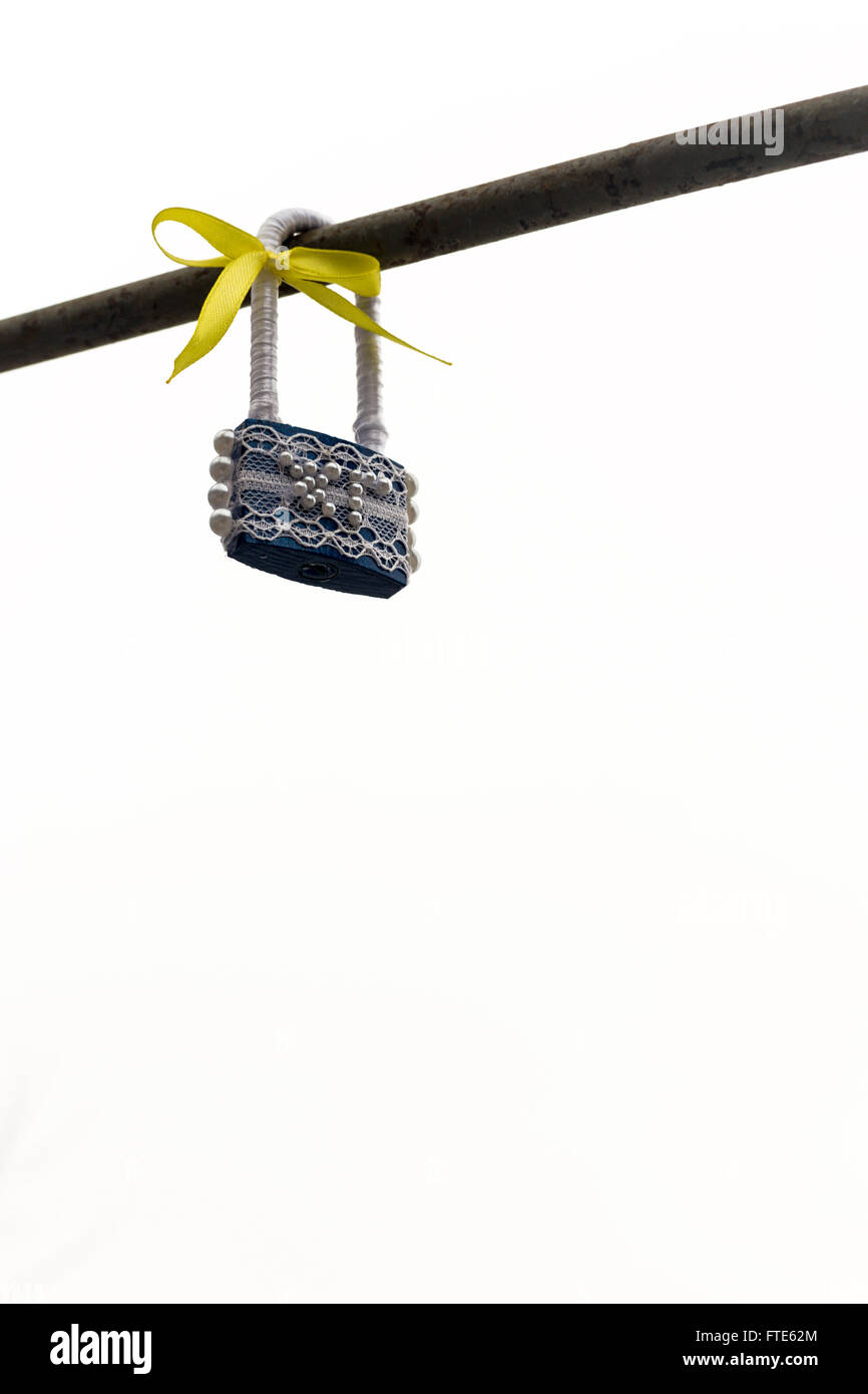 Cadenas scellés avec des imitations de perles fines et d'un bow jaune ruban est attaché à un rail métallique. Ciel gris avec copie espace salon f Banque D'Images