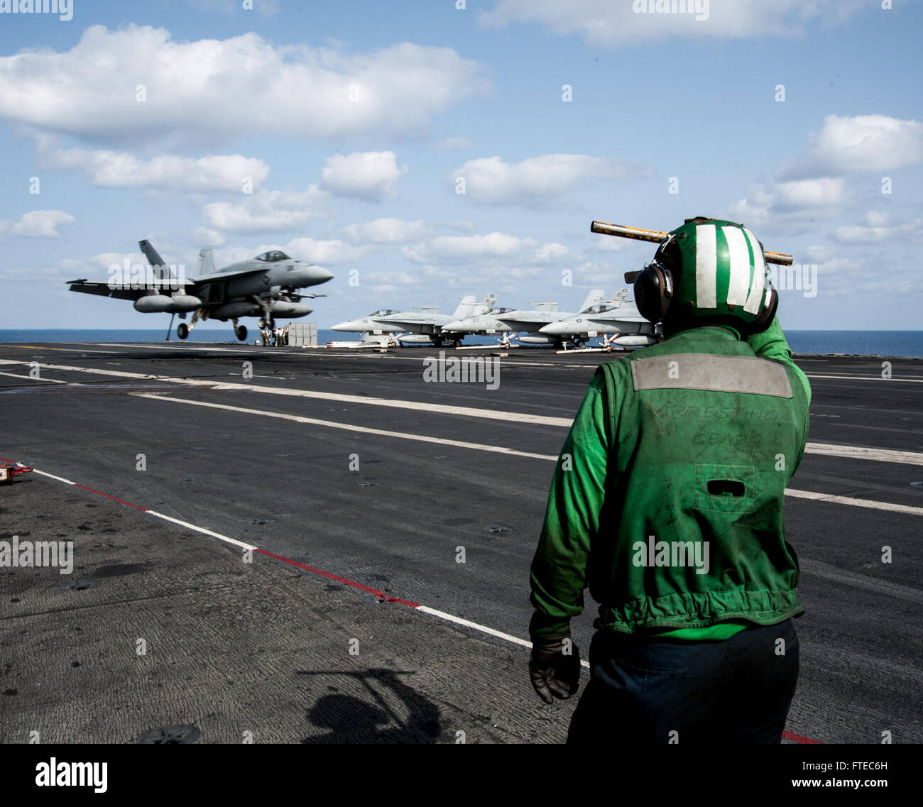 L'aviateur Justin Fortin de Titusville, en Floride, se prépare à récupérer le câble d'arrêt pendant qu'un F/A-18F Super Hornet du Strike Fighter Squadron (VFA) 213 se prépare à atterrir sur l'USS George H.W. Bush (CVN 77). Cette opération fait partie du déploiement du transporteur à l’appui des opérations de sûreté maritime dans la zone de la 6e flotte américaine. Banque D'Images