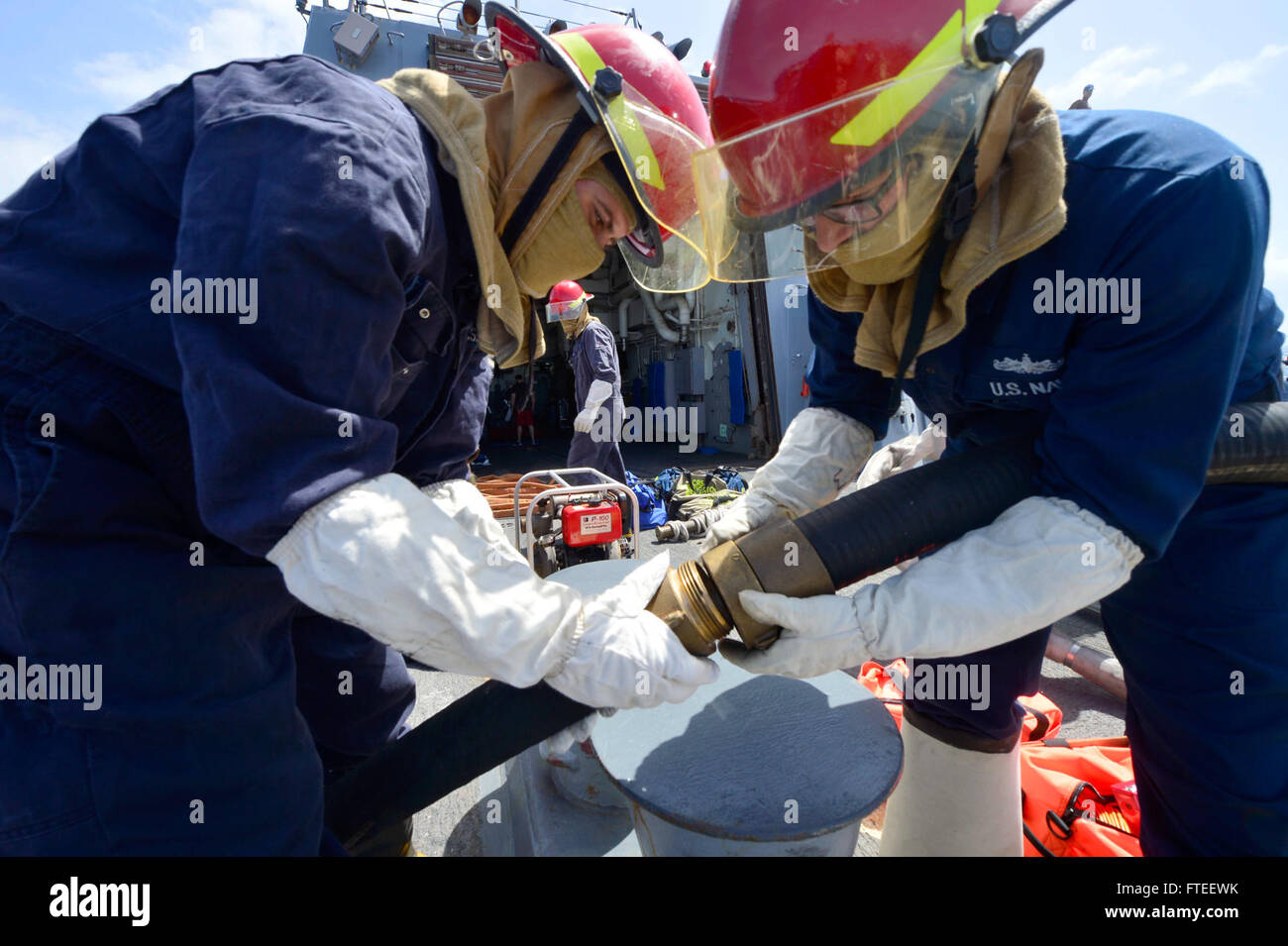 Kyle Taaffe, technicien en systèmes de turbines à gaz de 2e classe, et Timothy Monnier, contrôleur des dommages de 2e classe, à bord de l'USS *Nitze* (DDG 94), effectuent un exercice de contrôle des dommages le 9 juin 2014. L’exercice consiste à installer une pompe à eau P-100 lors d’opérations de sécurité maritime dans l’océan Indien. Banque D'Images