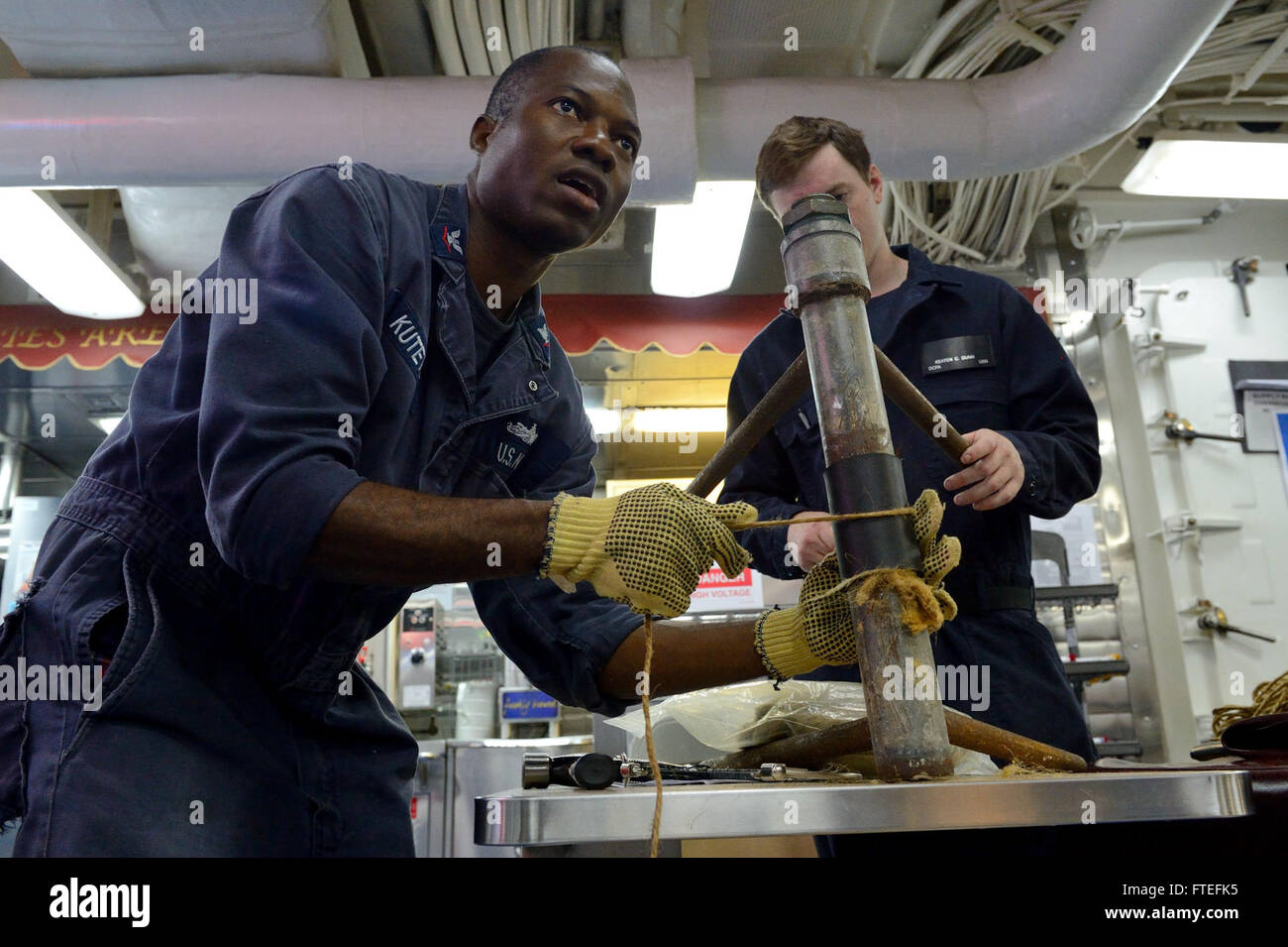 Cette image montre Damage Controlman 3rd Class Bamidele Kuteyi appliquant un patch de tuyau souple lors d'une séance d'entraînement à bord de l'USS Ross, un destroyer de missiles guidés. Le navire, stationné à Rota, en Espagne, soutient les opérations navales américaines en Europe. Banque D'Images