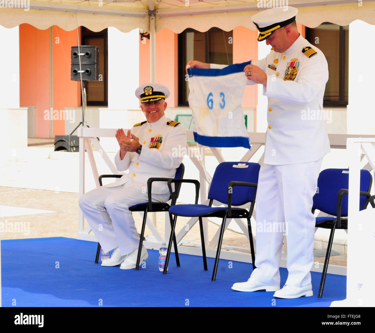 NAPLES, ITALIE (Août 21, 2013) - Capitaine John Rinko, gauche, applaudit comme le Capitaine Richard Soucie, commandant de la force militaire de la commande de transport maritime 63/l'Europe et l'Afrique (FCT63/MSCEURAF) affiche un fanion qu'il a reçu en cadeau lors d'une cérémonie de passation de commandement tenue sur la base navale américaine de Naples. Fct63/MSCEURAF exerce le contrôle tactique de l'ensemble des forces du Commandement de transport américain dans les théâtres européens et africains. Banque D'Images