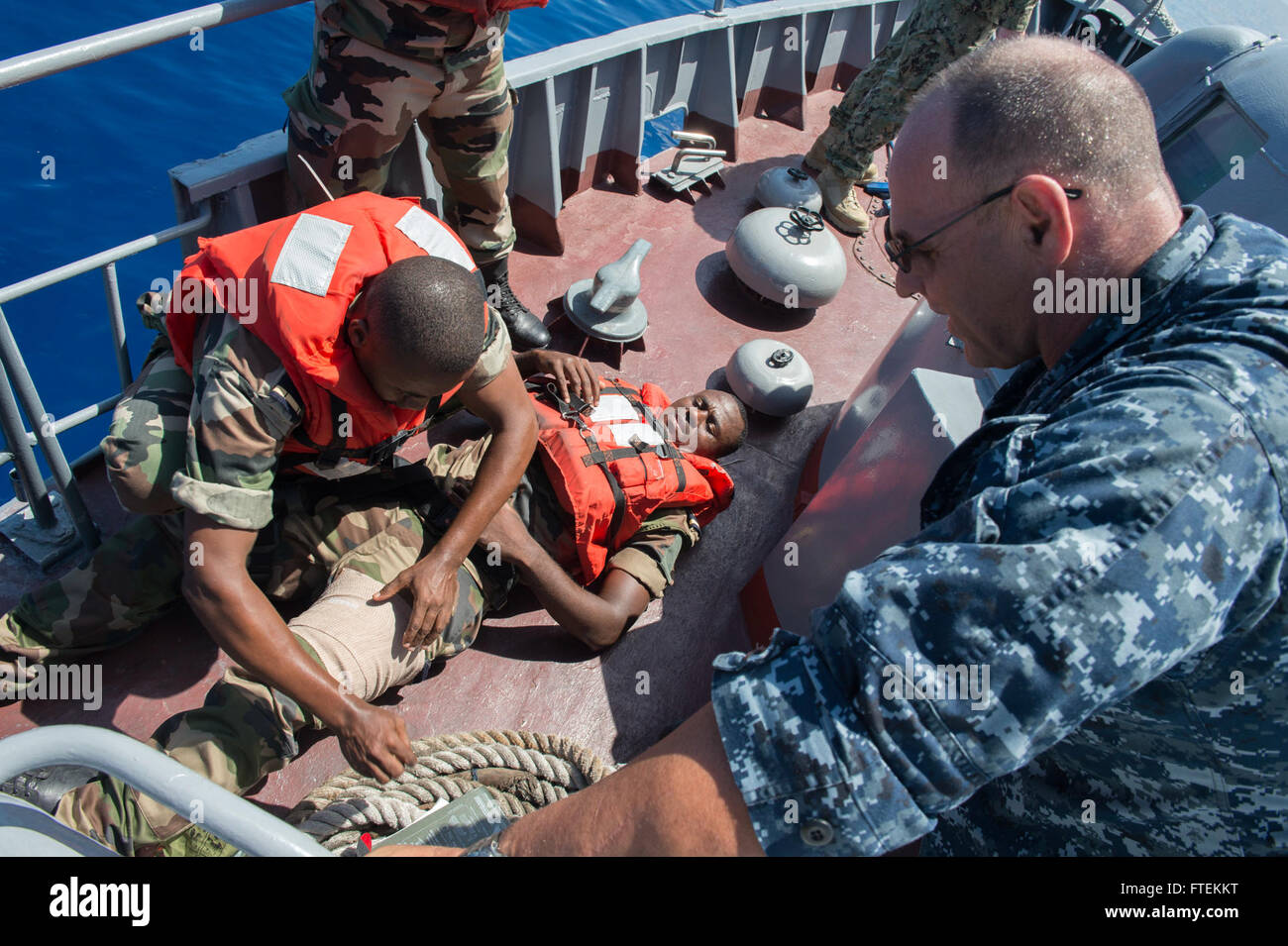 Un membre de l'équipe d'embarquement comorienne traite une blessure simulée tandis que le chef de l'hôpital Romeo Carrano supervise pendant la formation anti-piraterie à bord du patrouilleur mauricien CGS Rescuer. Ce scénario s’inscrit dans le cadre de l’exercice Cutlass Express 2015, qui vise à améliorer la coopération maritime et les opérations de lutte contre la piraterie en Afrique de l’est et dans l’océan Indien. Banque D'Images