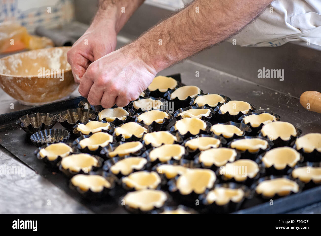Close Up de mâles non identifiables Baker Preparing Pastry pour les petites tartelettes - Pâtisserie Maison d'aplatissement dans Tarte individuels ébouriffé Banque D'Images