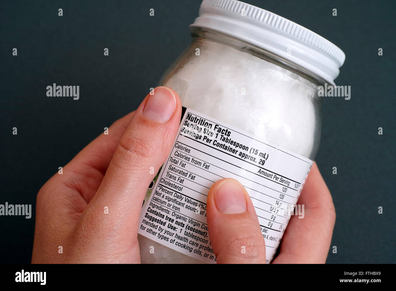 La lecture d'un tableau de la valeur nutritive sur l'huile de coco bio pot. Banque D'Images