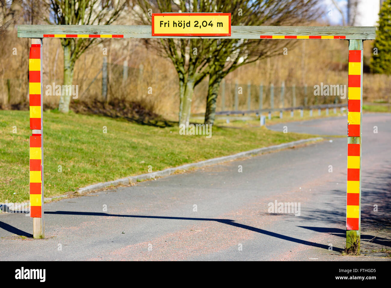 Un cadre en bois est un portail avec un avertissement au sujet de la hauteur disponible. Marquages couleurs jaune et rouge sur le portail. Banque D'Images