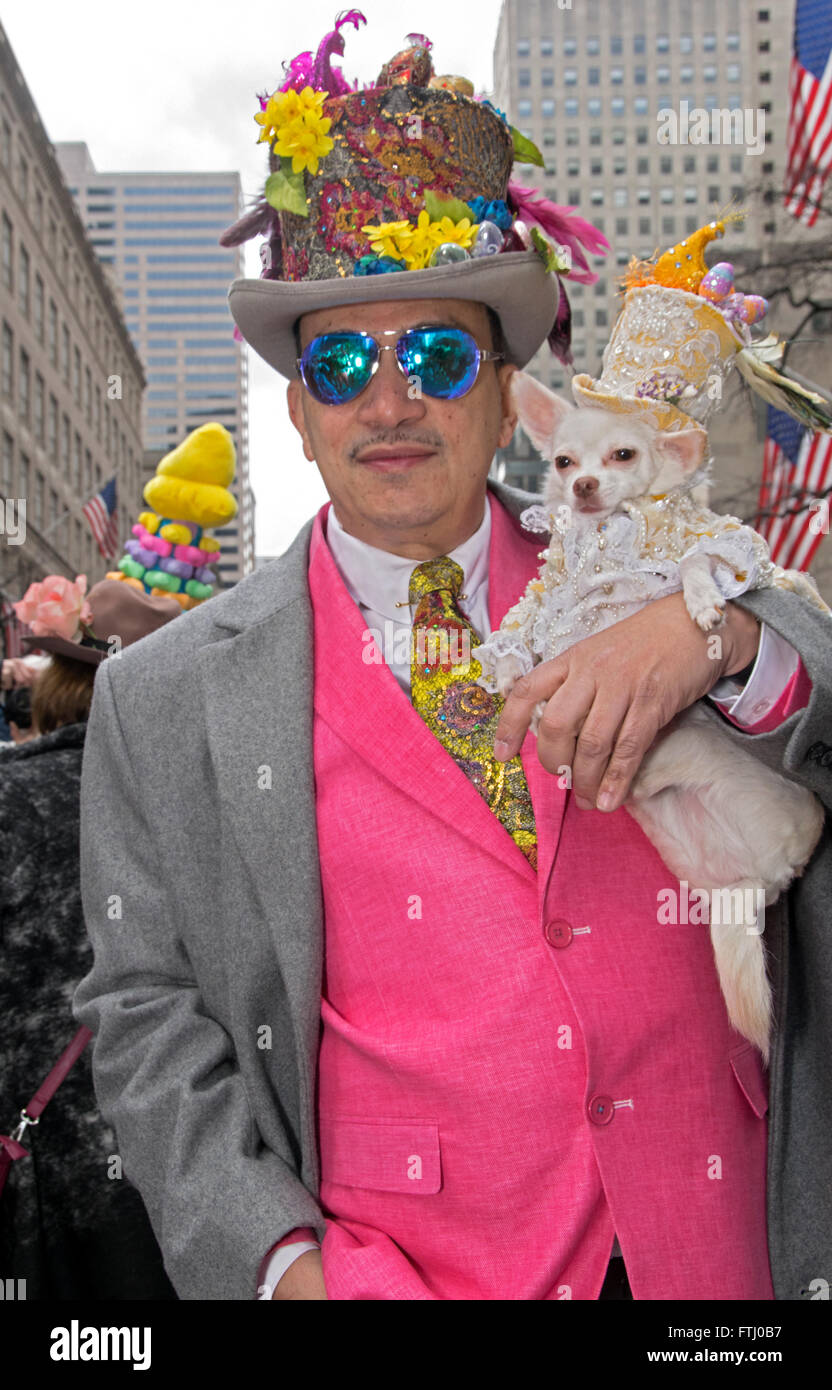 Un homme dans un drôle de bonnet et gilet rose avec son petit chien blanc sur la Cinquième Avenue à Manhattan pour l'Easter Parade. Banque D'Images