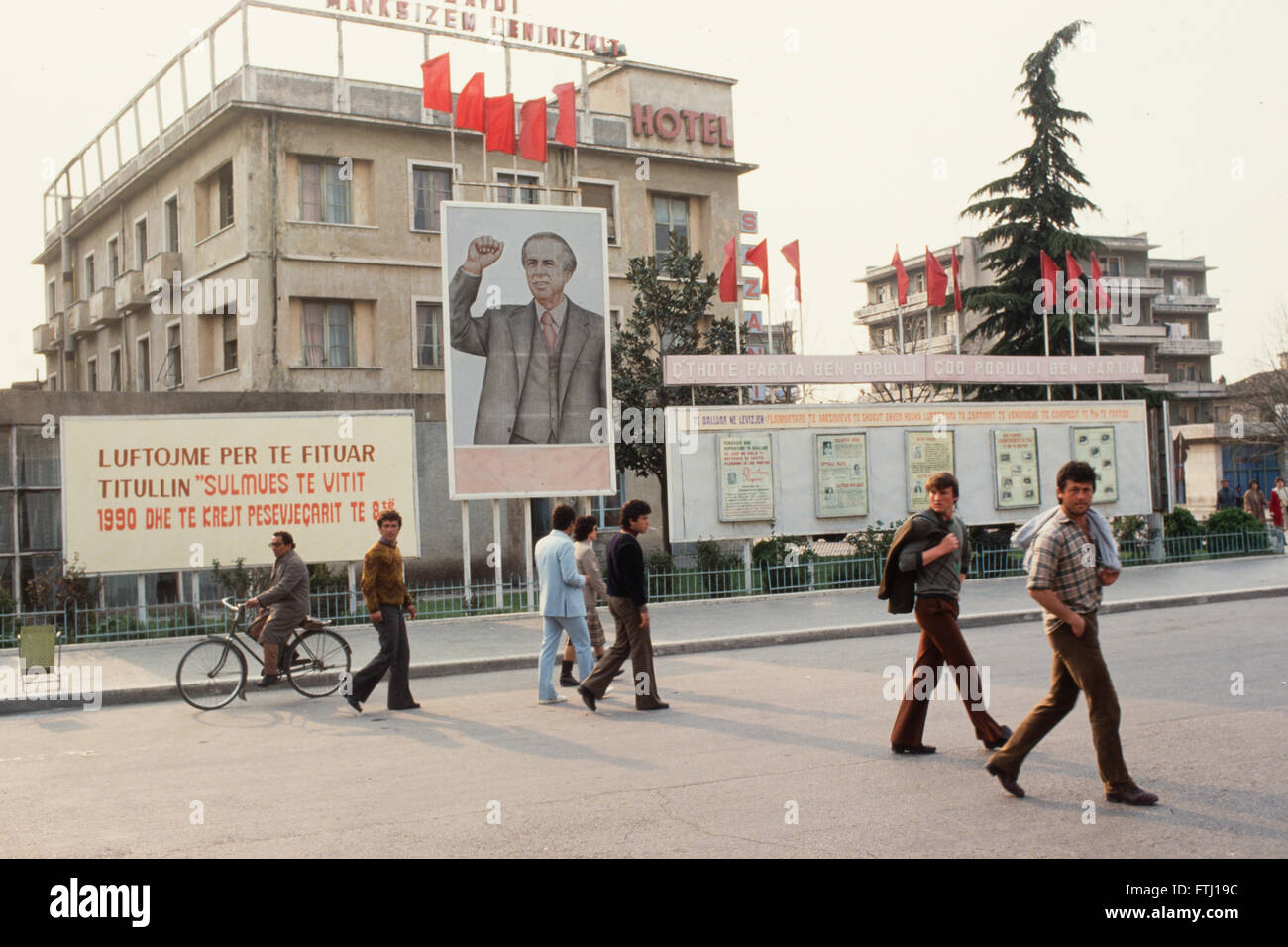 Les gens passent devant les slogans du parti communiste à l'extérieur de l'hôtel dans la ville côtière de Vlora. Banque D'Images