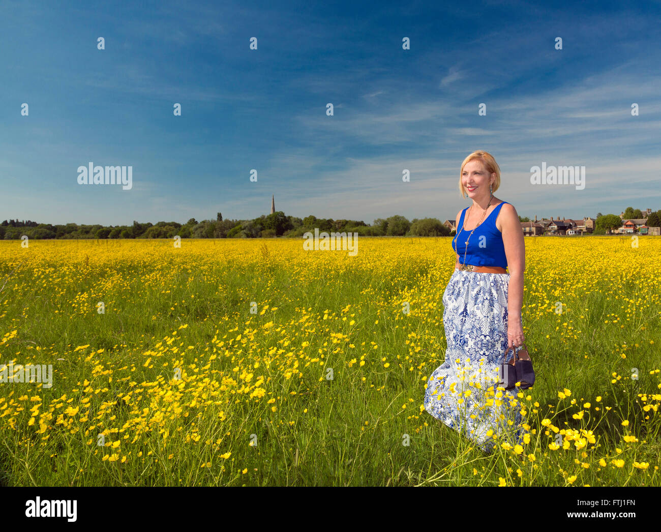 Femme debout dans une prairie avec des fleurs de renoncule Banque D'Images