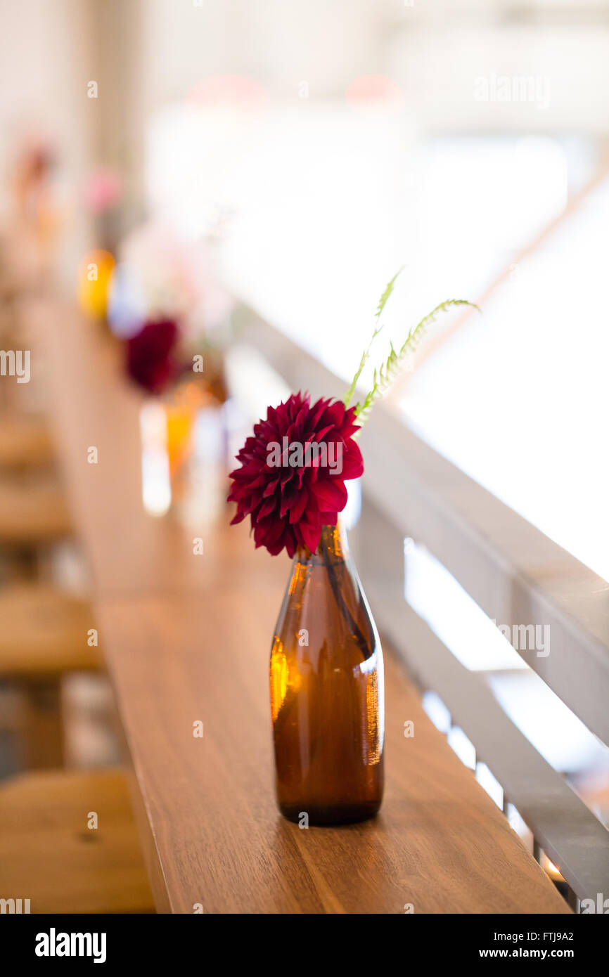 Des fleurs de mariage sur les tables de réception d'installation par un fleuriste à l'aide de bouteilles antiques vintage. Banque D'Images