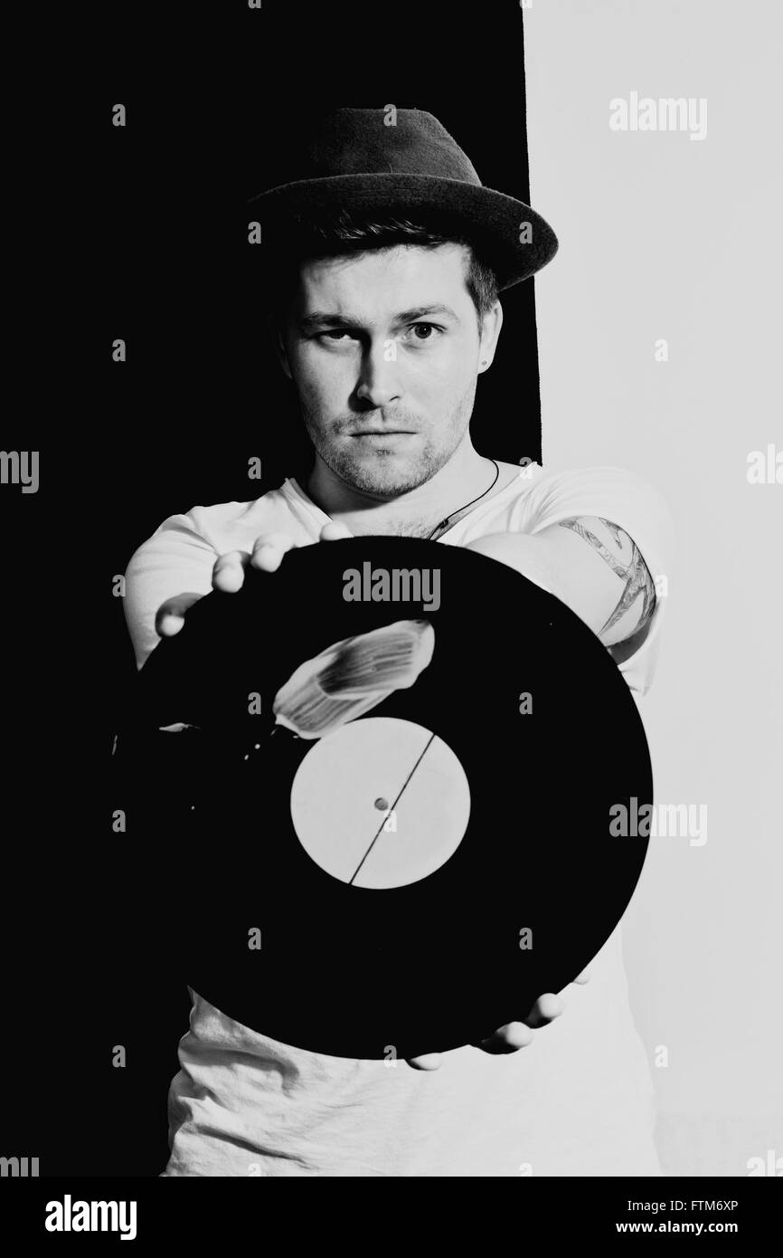 Portrait d'un jeune homme avec un disque vinyle sur un fond noir Banque D'Images