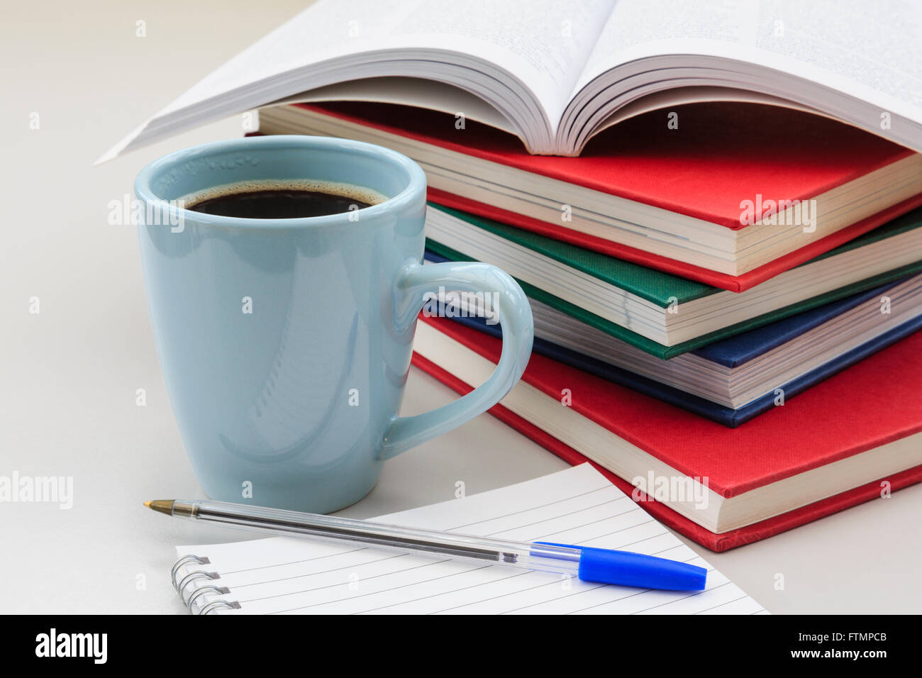 Scène d'études de l'étudiant avec des tas de livres et tasse de café noir fort par un carnet et un stylo sur un bureau de révision pour les examens. Angleterre Royaume-uni Grande-Bretagne Banque D'Images