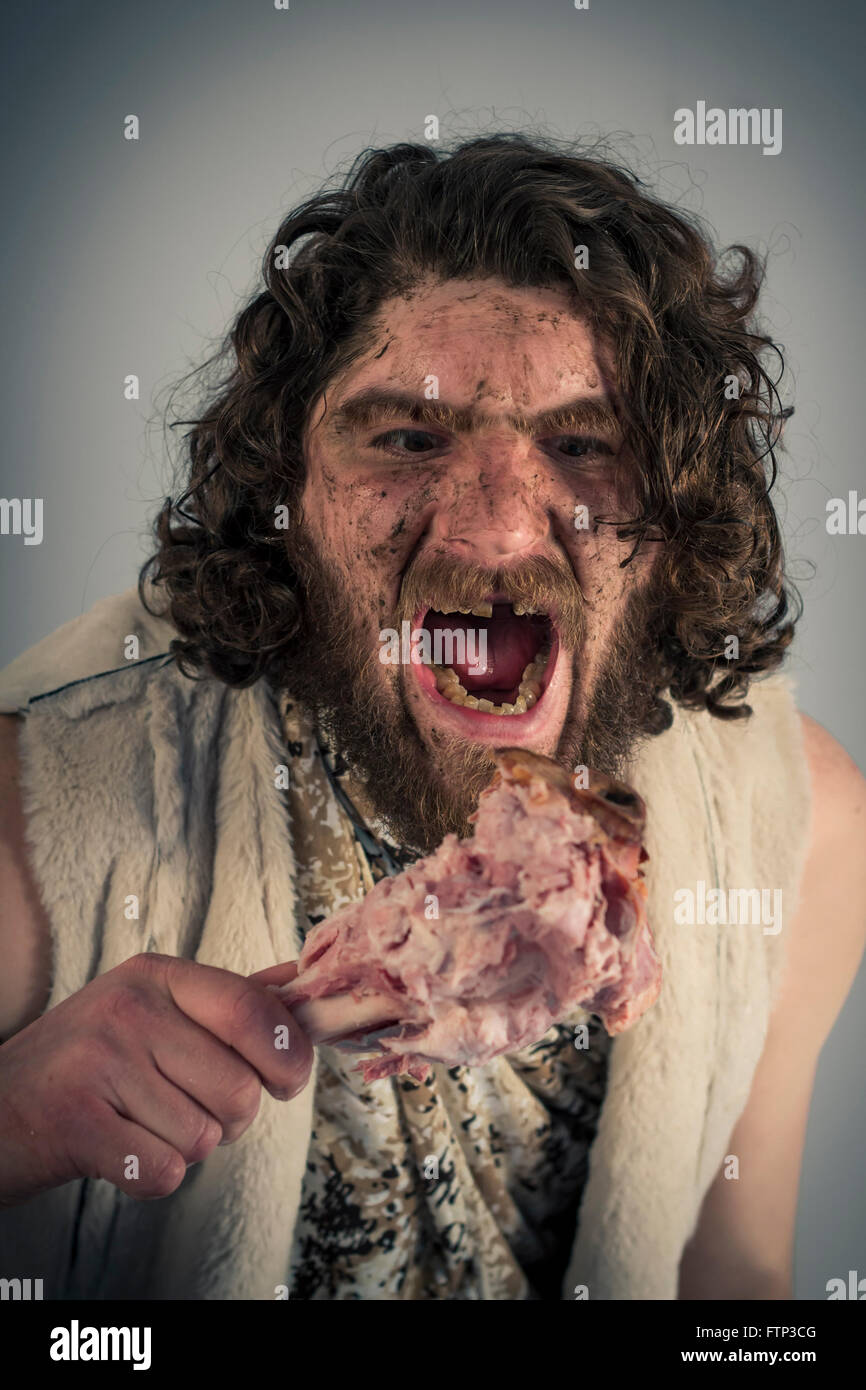 Grotte de la faim stupide man eating ham sur l'os Banque D'Images