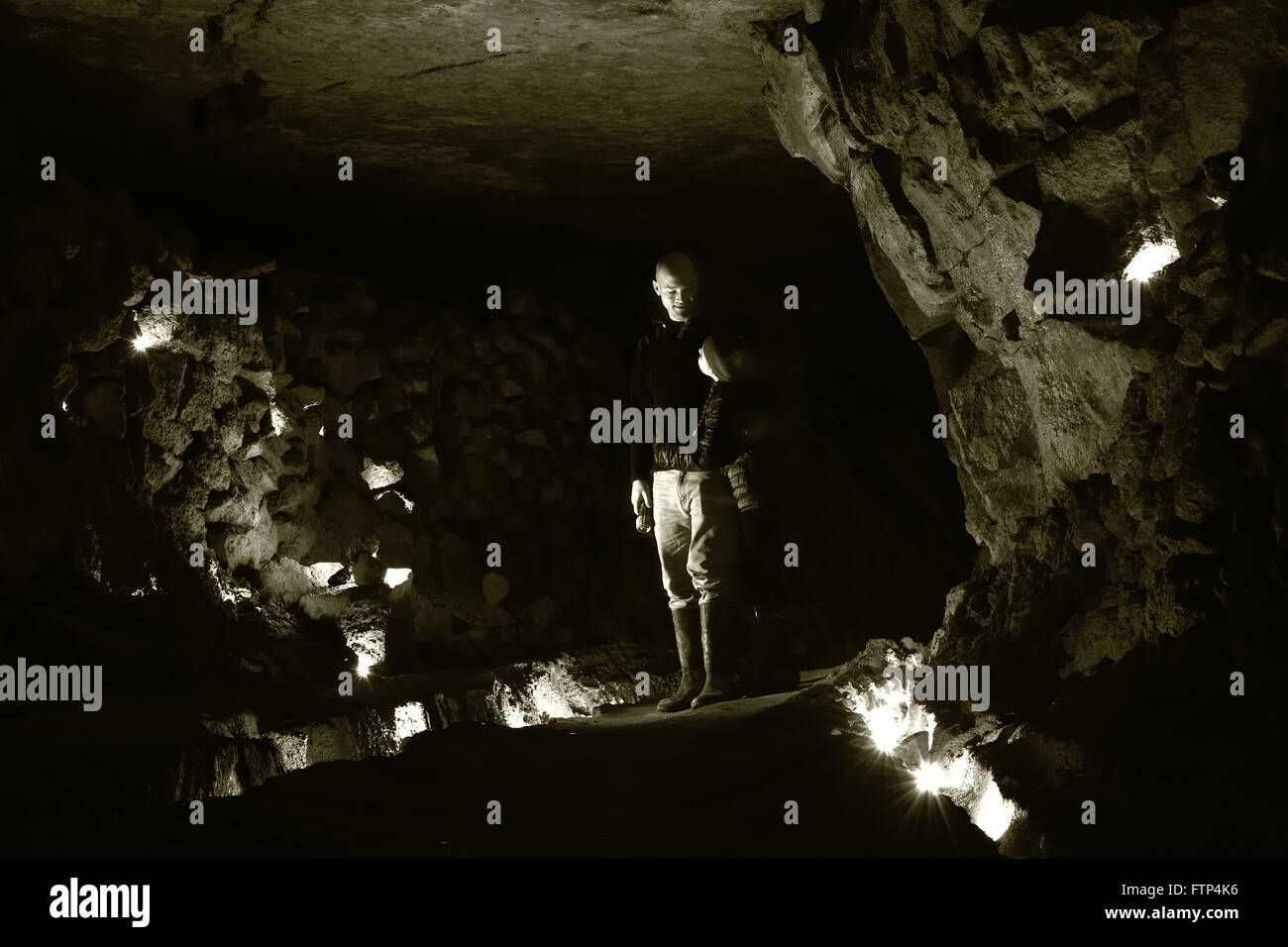 Homme et enfant sous terre dans une mine abandonnée. Une fille et grand homme serrant dans un tunnel d'une ancienne mine de calcaire, dans le Wiltshire Banque D'Images