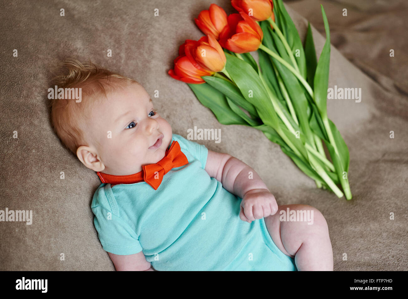 Petit garçon allongé sur le lit avec un bouquet de tulipes Banque D'Images