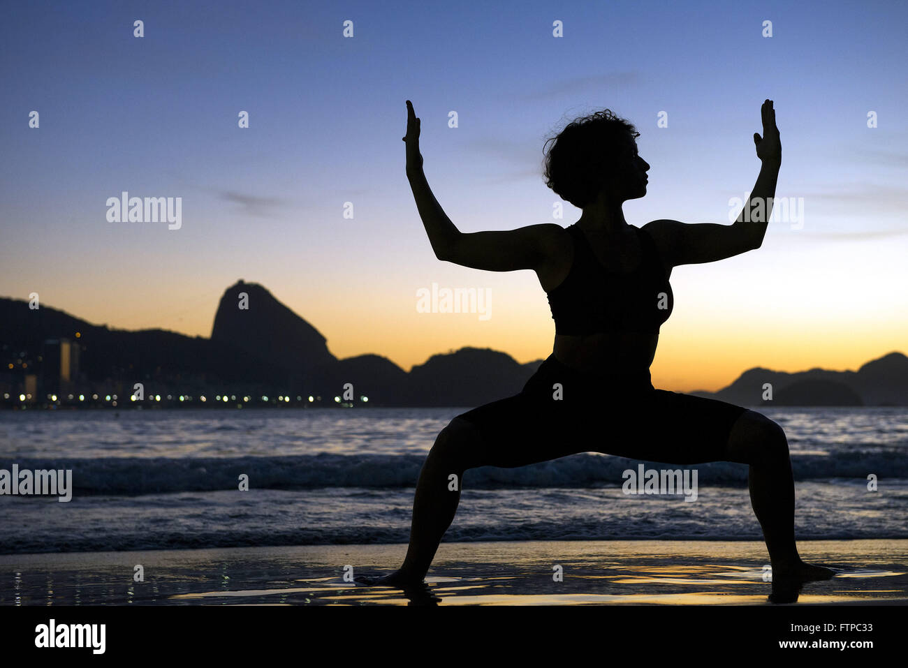 Mulher em posent de yoga na Praia de Copacabana ao amanhecer - zona sul Banque D'Images