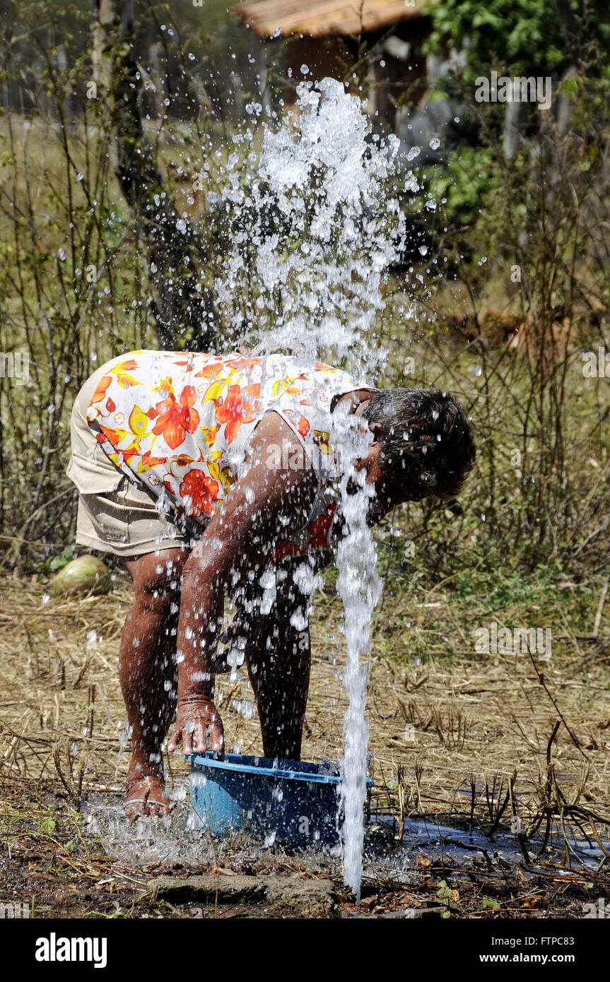 Femme avec de l'eau d'où la masse et effectué le Cowboy de laver des vêtements Banque D'Images