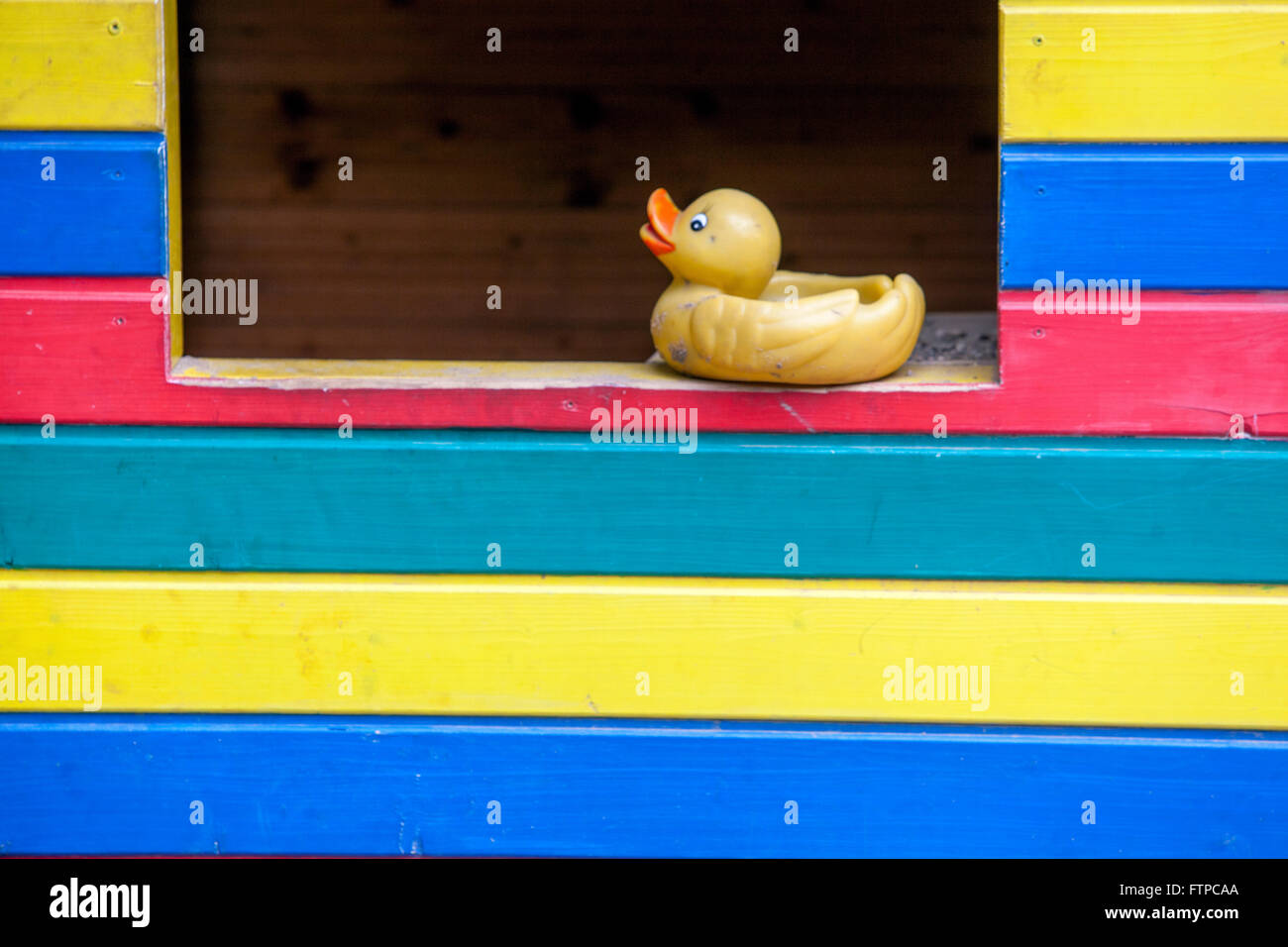 Canard en caoutchouc, jouet en plastique sur une fenêtre en bois colorée à rayures maison de cubby Banque D'Images
