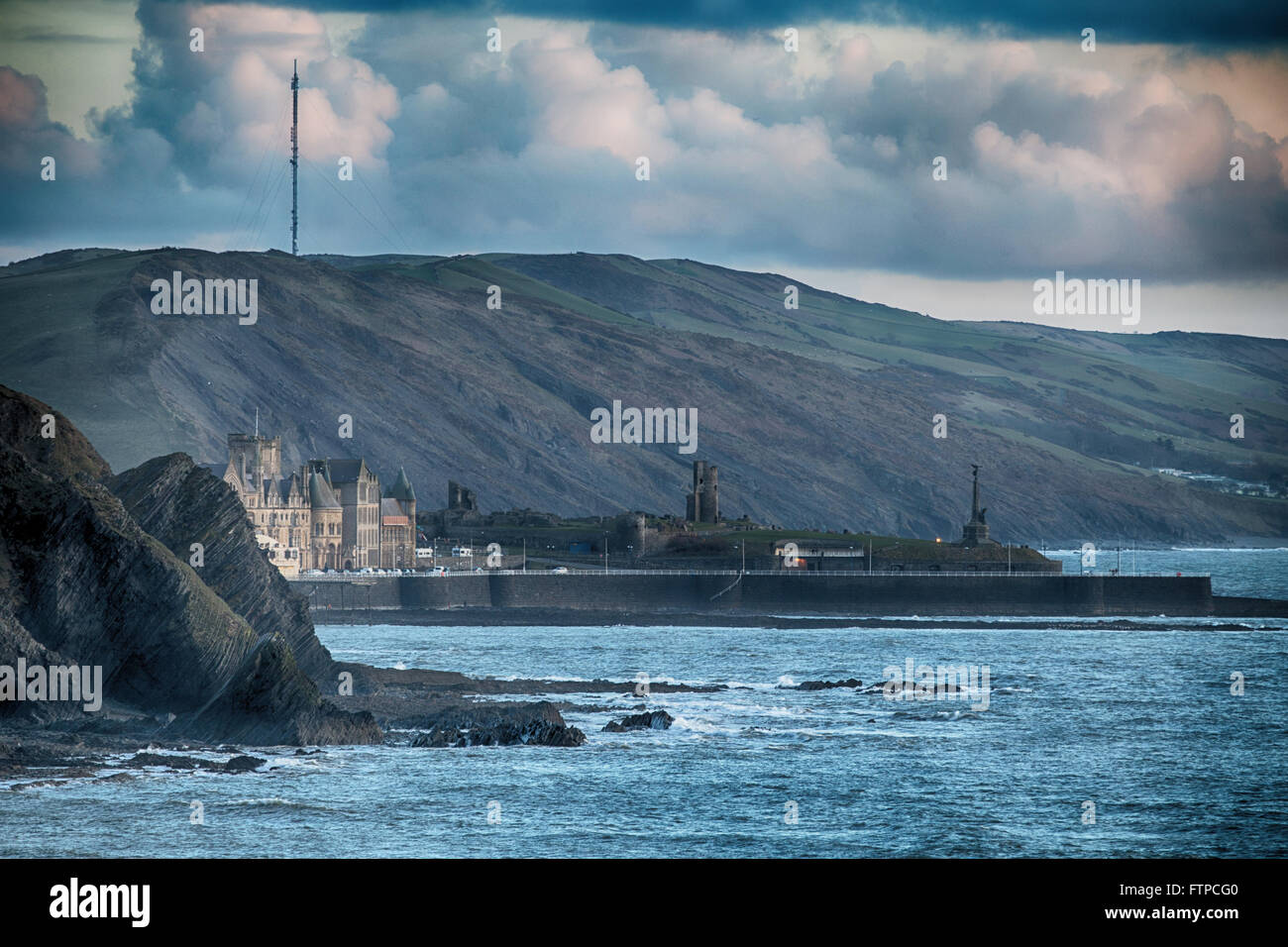 Ancien Collège d'Aberystwyth, mémorial de la guerre et le château vu du nord au crépuscule, avec Blaenplwyf émetteur de télévision derrière le mât. Banque D'Images