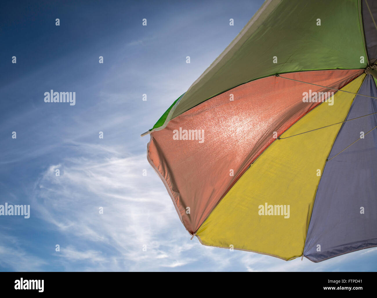 Parasol coloré ouvert contre un ciel bleu ensoleillé Banque D'Images