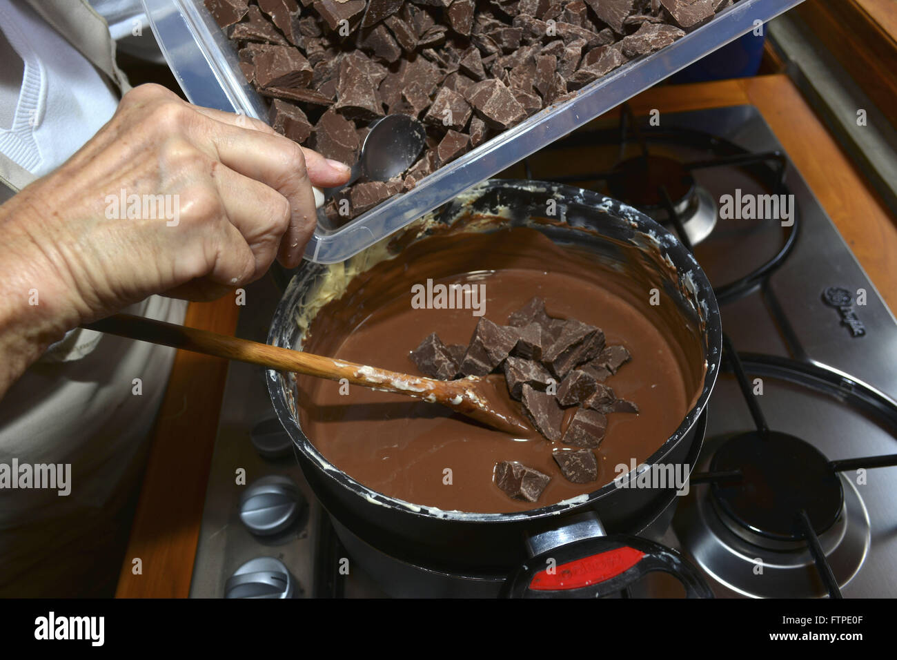Woman pouring morceaux de chocolat en pot production d'oeufs de Pâques à la main Banque D'Images