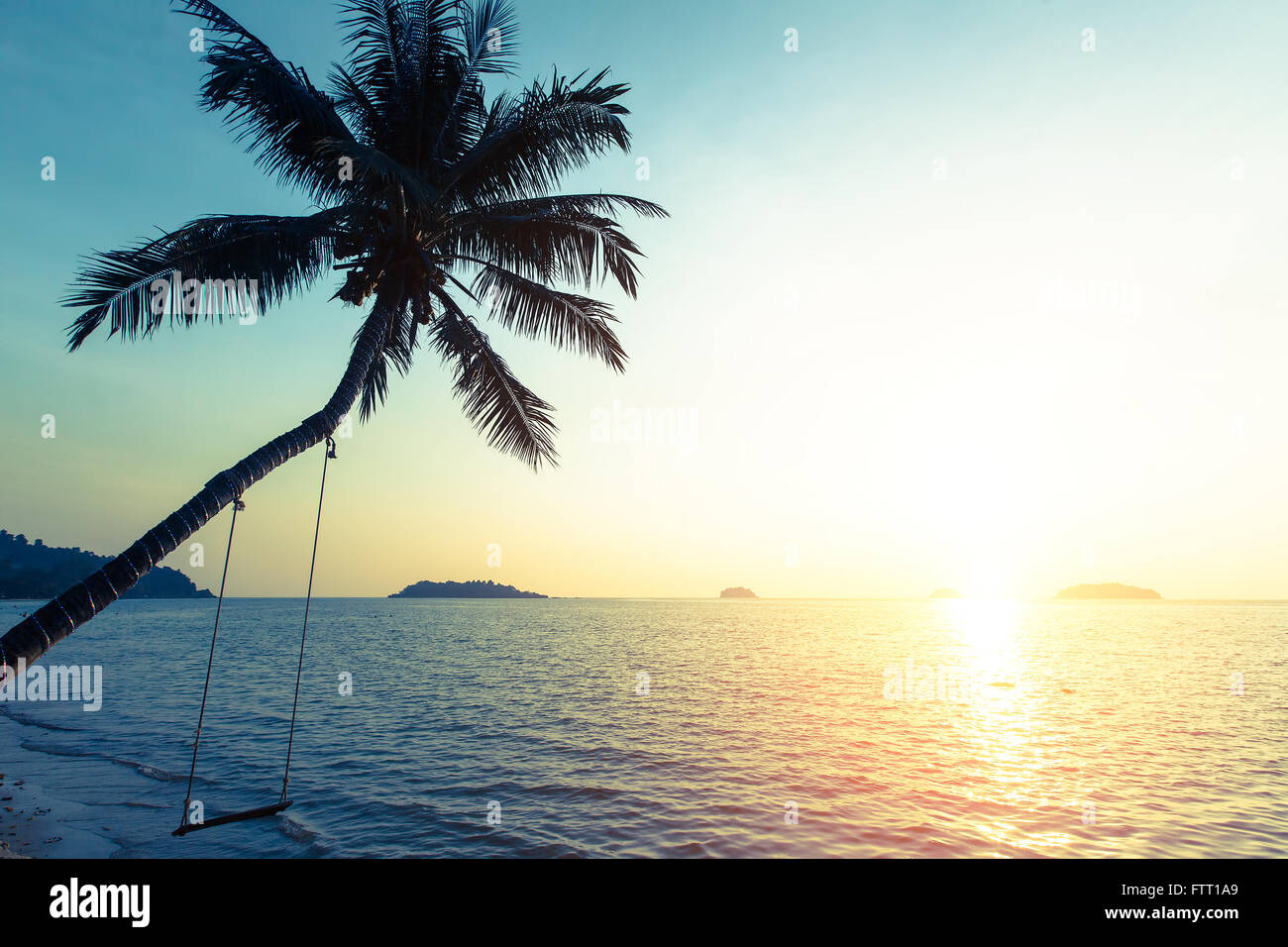 Coucher du soleil sur la côte tropicale, la silhouette du palmier sur l'eau. Banque D'Images